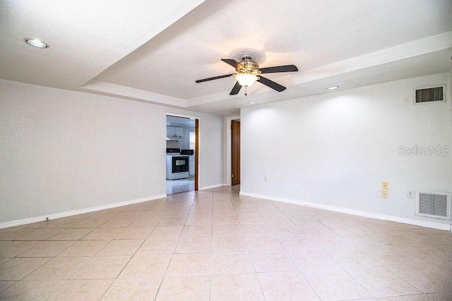 unfurnished room with a raised ceiling, light tile patterned flooring, and ceiling fan