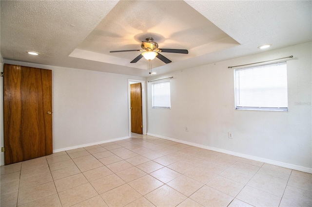 tiled spare room with ceiling fan, a raised ceiling, and a textured ceiling