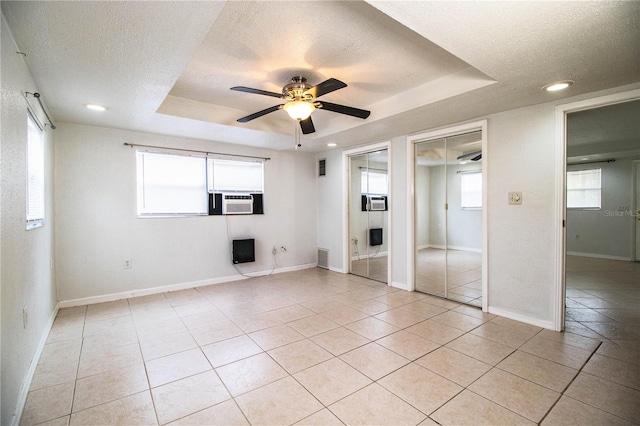 unfurnished bedroom featuring ceiling fan, a raised ceiling, a textured ceiling, and light tile patterned floors