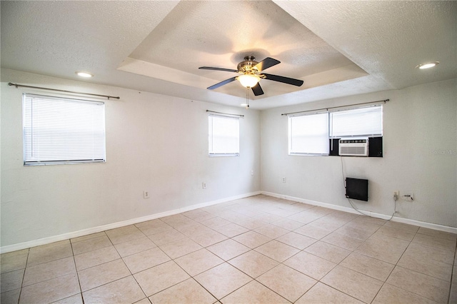 tiled empty room with cooling unit, ceiling fan, a raised ceiling, and a textured ceiling