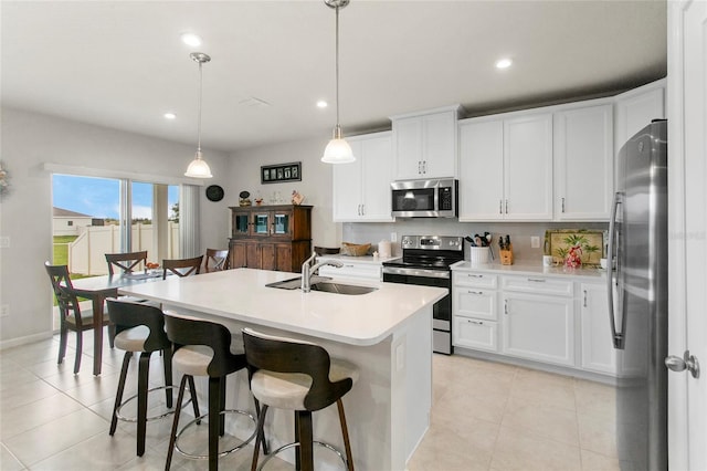 kitchen with appliances with stainless steel finishes, hanging light fixtures, and white cabinetry