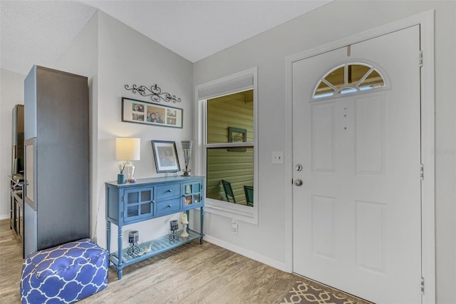 foyer with light wood-style flooring and baseboards