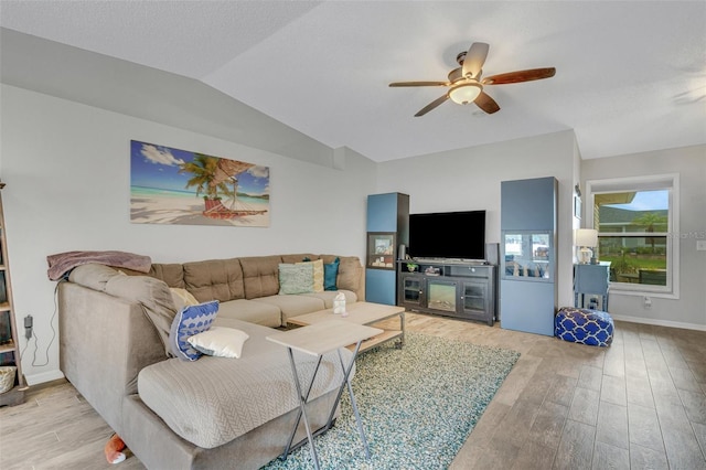 living room with vaulted ceiling, ceiling fan, light wood-type flooring, and baseboards