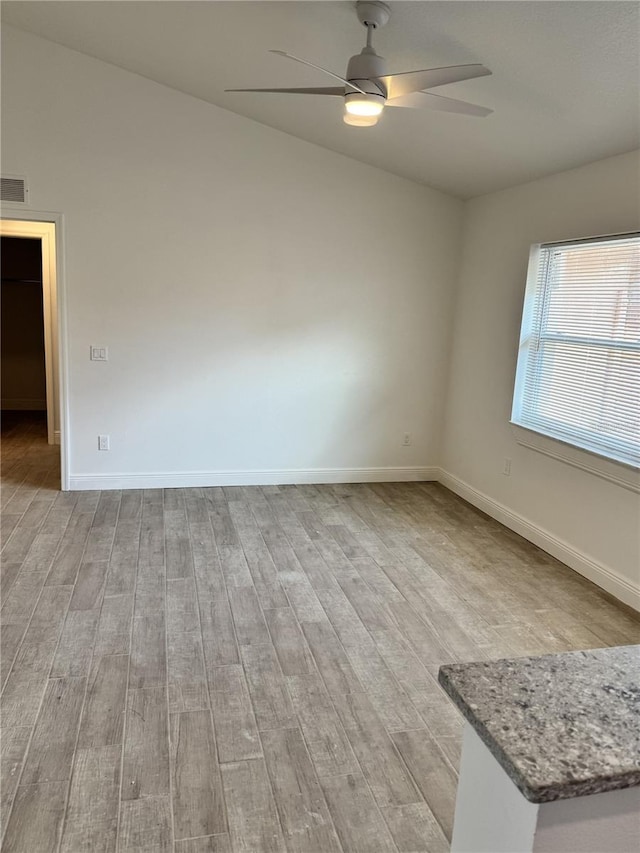 unfurnished room with light wood-style floors, baseboards, visible vents, and ceiling fan