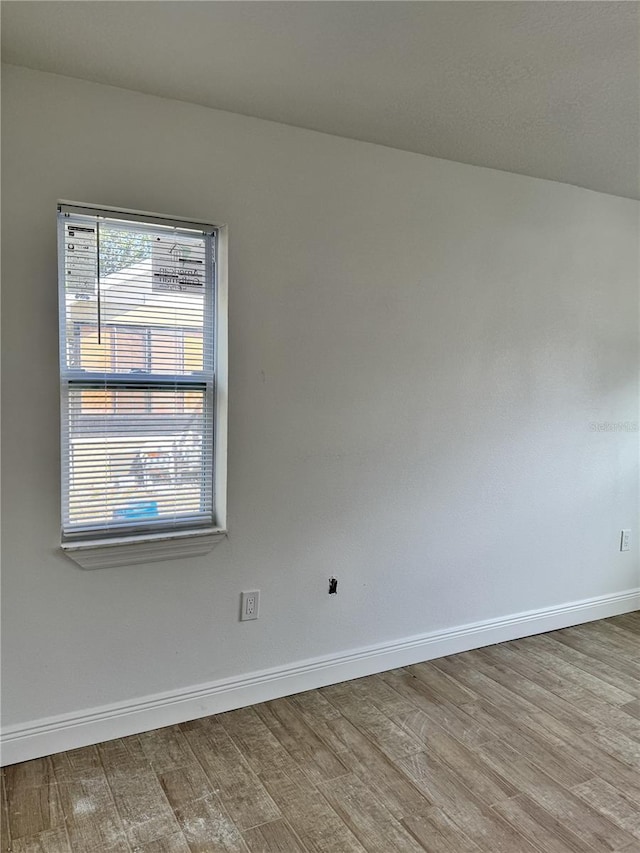 spare room with baseboards and light wood-style floors