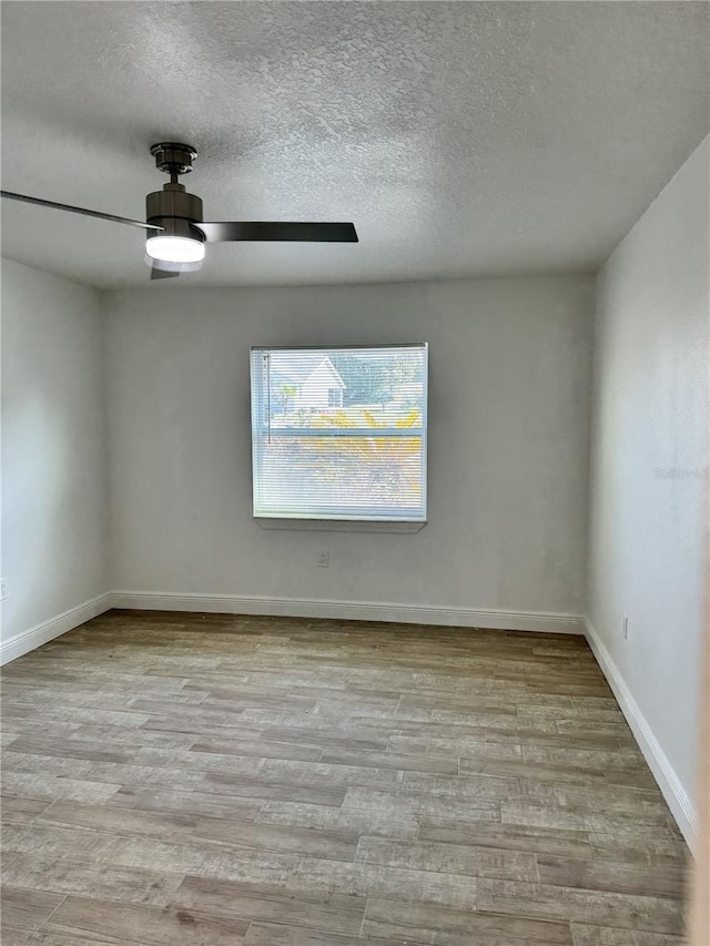 unfurnished room featuring a textured ceiling, light wood-type flooring, a ceiling fan, and baseboards