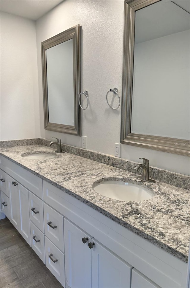 bathroom with double vanity, a sink, and wood finished floors