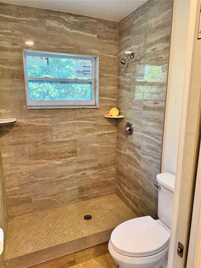 bathroom with toilet and a tile shower