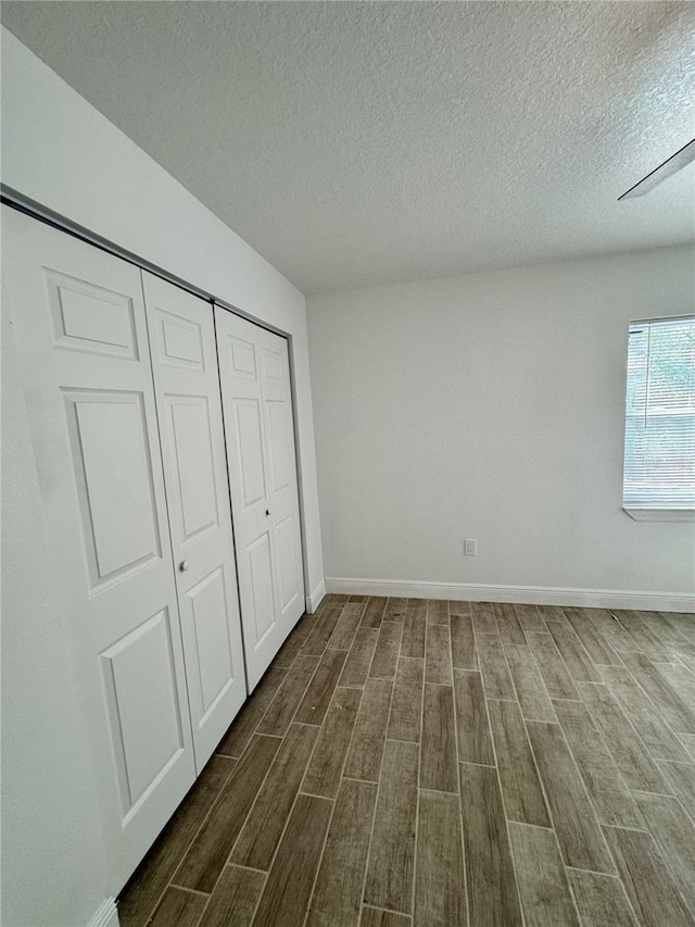 unfurnished bedroom featuring baseboards, a closet, and wood finish floors