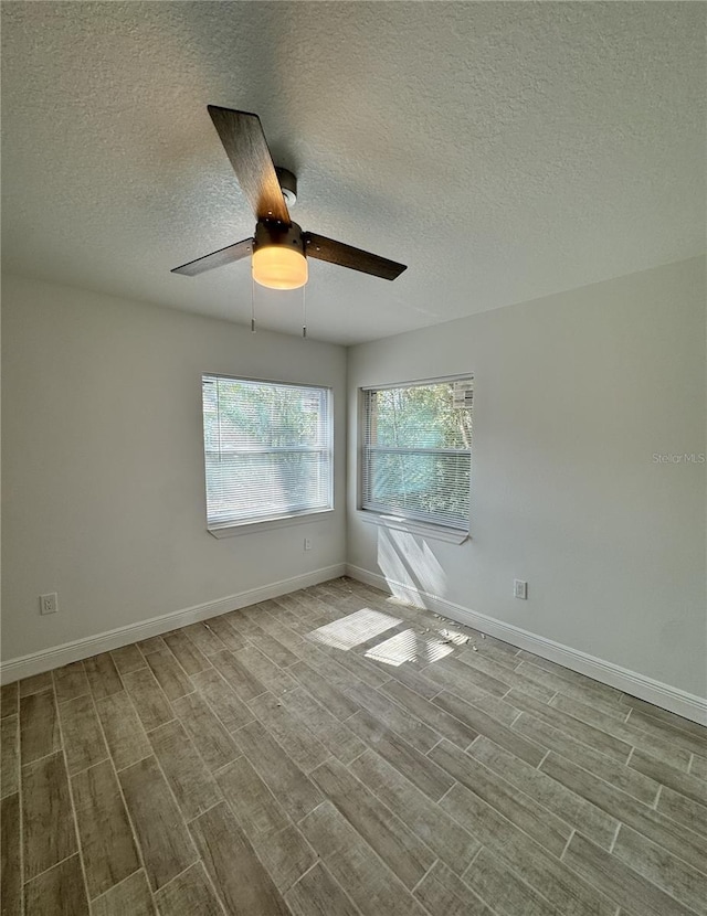 empty room featuring light wood-style flooring, baseboards, ceiling fan, and a textured ceiling