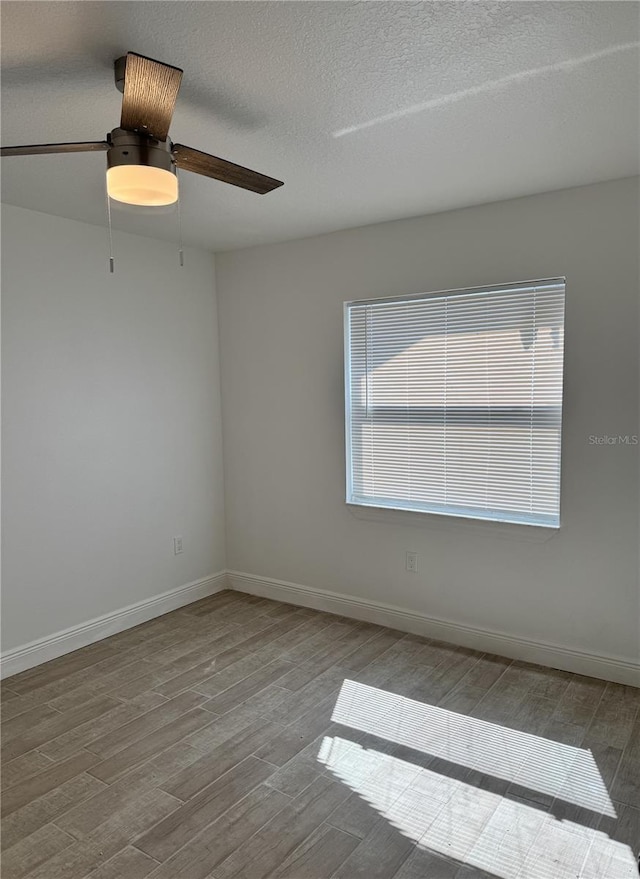 unfurnished room with a textured ceiling, ceiling fan, light wood-type flooring, and baseboards