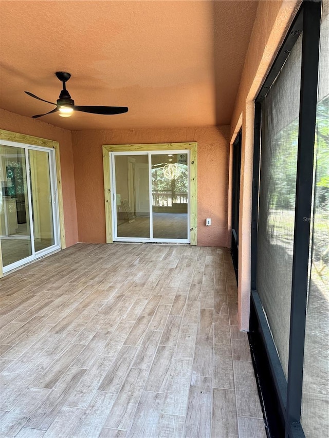 unfurnished sunroom with ceiling fan