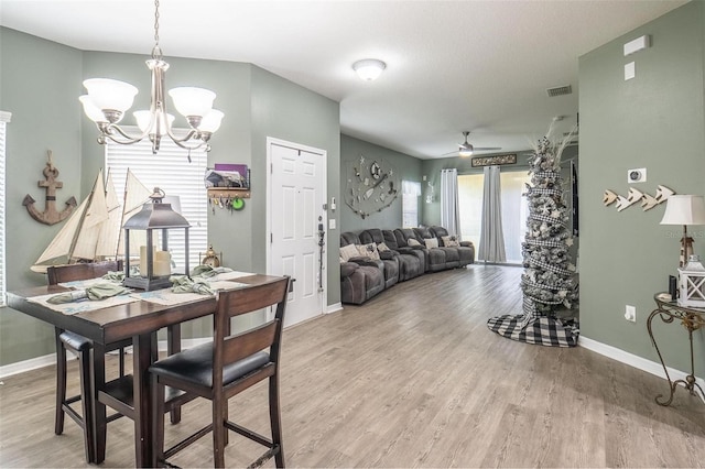 dining space with ceiling fan with notable chandelier and hardwood / wood-style flooring