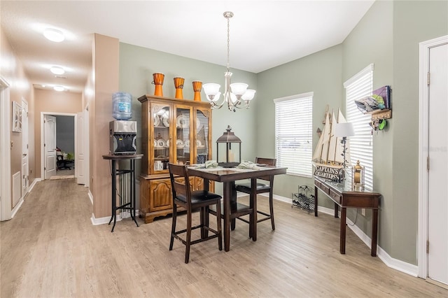 dining room with light wood-type flooring and a chandelier