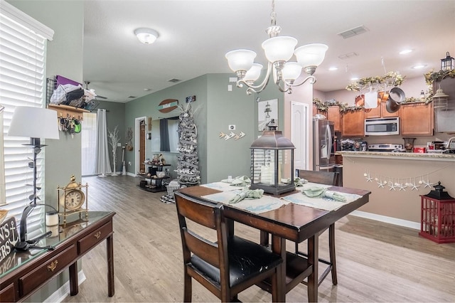 dining space featuring light hardwood / wood-style floors and ceiling fan with notable chandelier