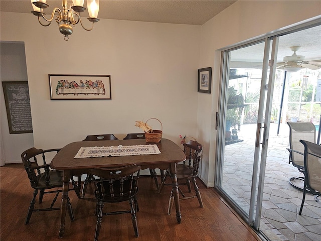 dining area with hardwood / wood-style flooring, ceiling fan with notable chandelier, and a textured ceiling