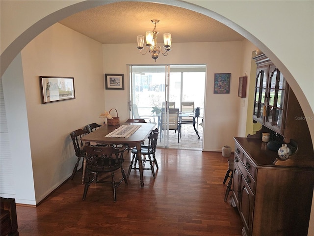 dining area with a notable chandelier, dark wood-type flooring, and a textured ceiling