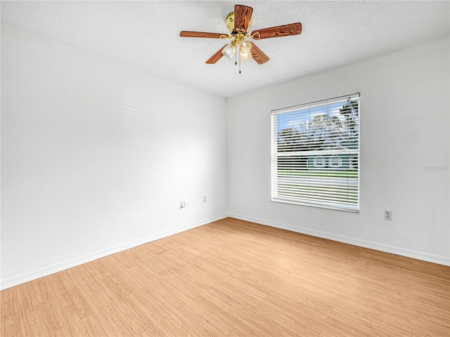 spare room with baseboards, a textured ceiling, and light wood finished floors