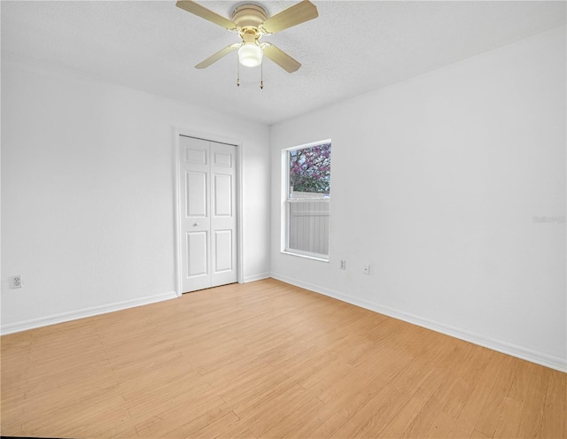 spare room featuring baseboards, ceiling fan, a textured ceiling, and light wood-style floors