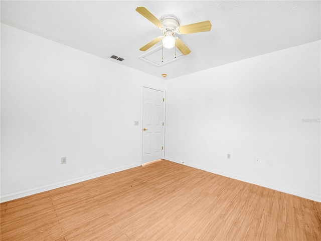 unfurnished room featuring light wood finished floors, attic access, visible vents, and baseboards