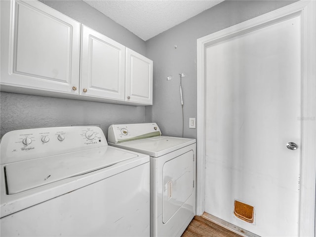 laundry room with washing machine and dryer, cabinet space, a textured ceiling, and wood finished floors