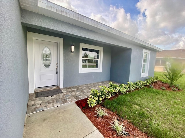 entrance to property with covered porch and stucco siding