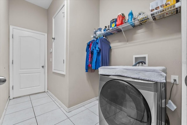 clothes washing area featuring washer / dryer, baseboards, light tile patterned floors, and laundry area