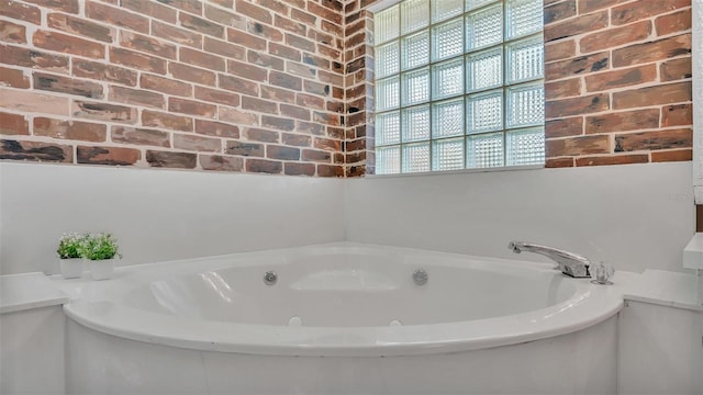 bathroom with tiled bath and brick wall