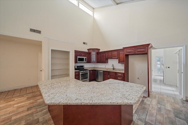 kitchen with stainless steel appliances, a center island, sink, and dark wood-type flooring