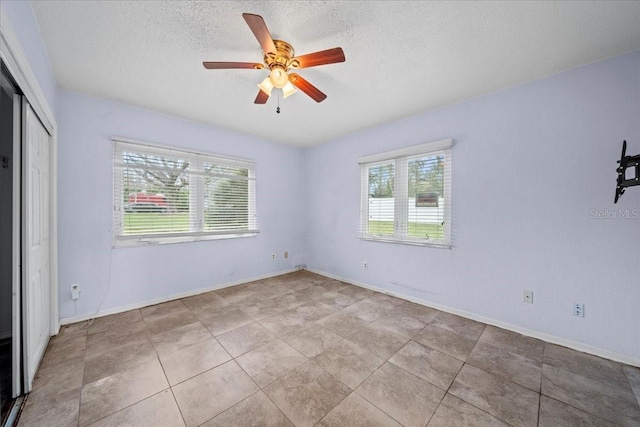 empty room featuring ceiling fan, a textured ceiling, and a healthy amount of sunlight