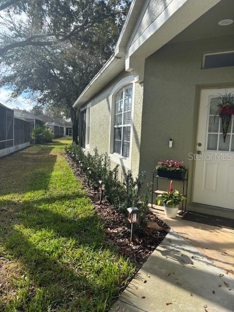 8623 Snowy Owl Way, Tampa, FL 33647 - view of side of property featuring stucco siding and a lawn