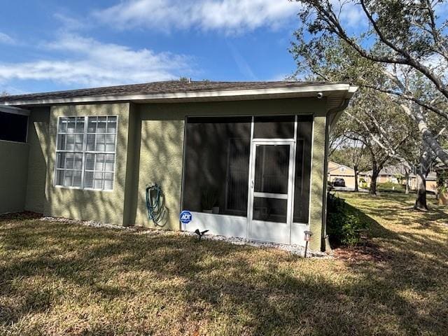 8623 Snowy Owl Way, Tampa, FL 33647 - view of side of home featuring stucco siding, a sunroom, and a lawn