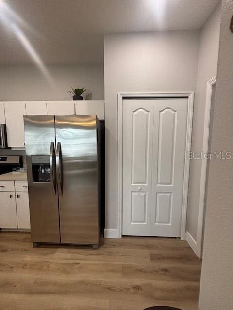 8623 Snowy Owl Way, Tampa, FL 33647 - kitchen with light wood-type flooring, white cabinetry, light countertops, and stainless steel fridge