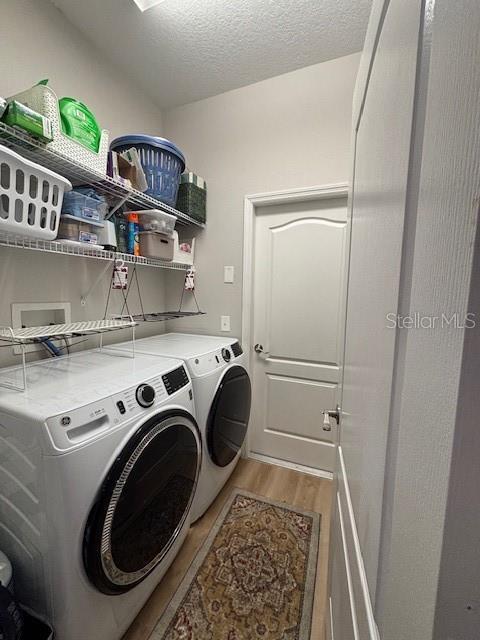 8623 Snowy Owl Way, Tampa, FL 33647 - clothes washing area with washing machine and clothes dryer, light wood finished floors, laundry area, and a textured ceiling