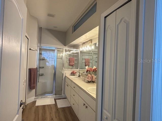 8623 Snowy Owl Way, Tampa, FL 33647 - full bathroom with baseboards, a sink, double vanity, wood finished floors, and a stall shower