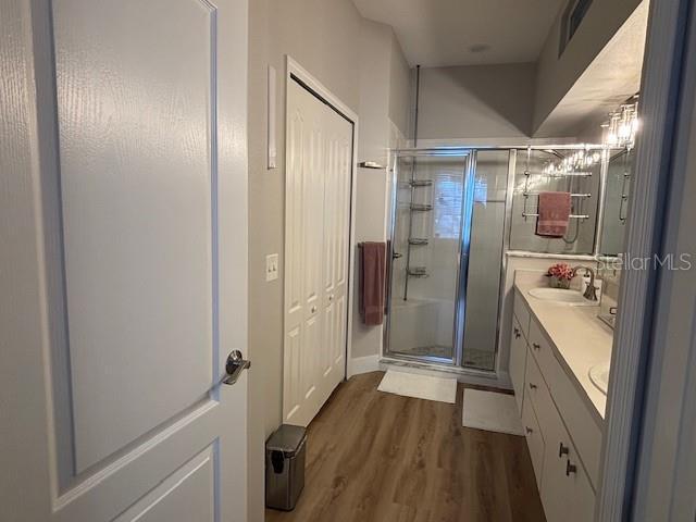 8623 Snowy Owl Way, Tampa, FL 33647 - bathroom featuring baseboards, double vanity, a stall shower, a sink, and wood finished floors