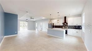 kitchen featuring white cabinetry, stainless steel refrigerator, a kitchen island, pendant lighting, and range hood