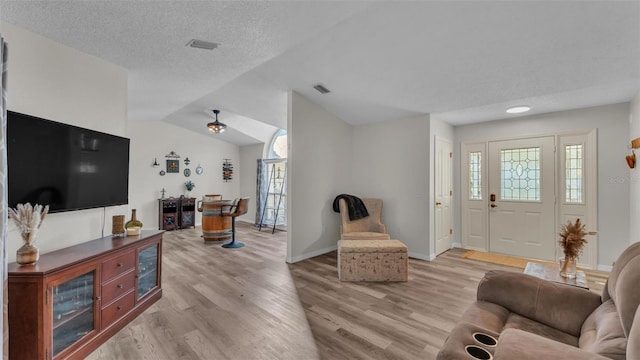 living room with vaulted ceiling, plenty of natural light, and light hardwood / wood-style floors