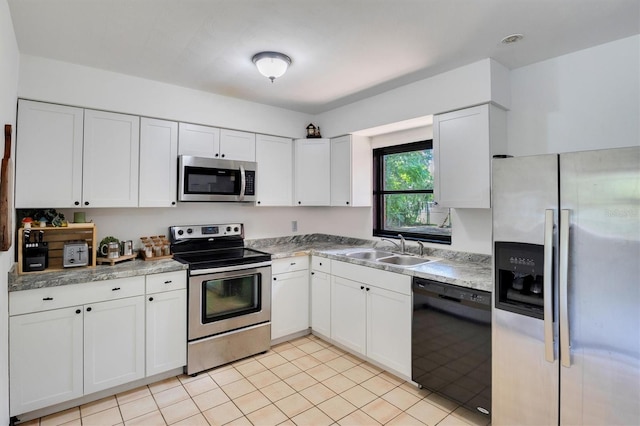 kitchen with light tile patterned floors, appliances with stainless steel finishes, sink, and white cabinets