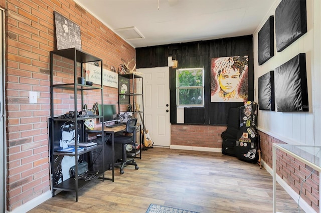 home office featuring wooden walls, light hardwood / wood-style floors, and brick wall