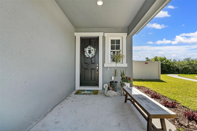 doorway to property featuring a lawn and stucco siding