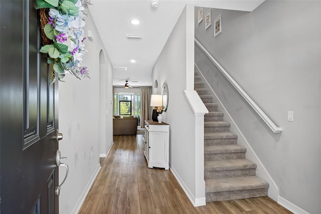 entrance foyer featuring stairway, wood finished floors, visible vents, baseboards, and arched walkways