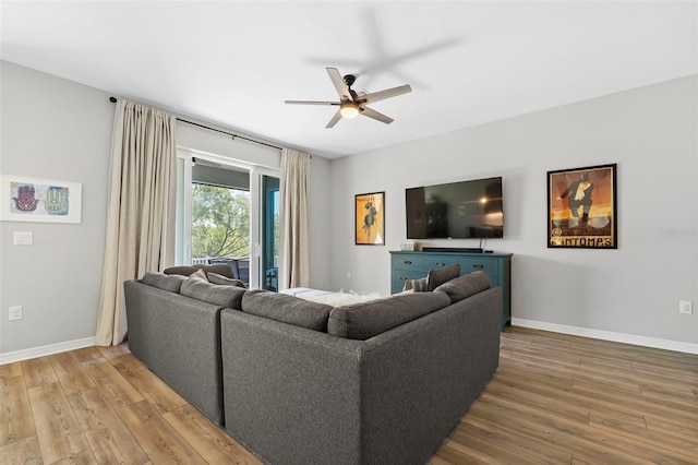 living room featuring wood finished floors, baseboards, and ceiling fan