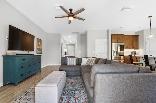 living area with a ceiling fan, wood finished floors, visible vents, and baseboards