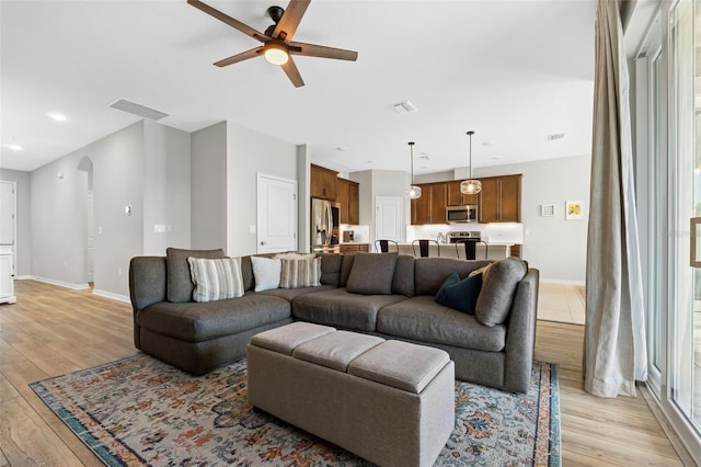 living room with visible vents, arched walkways, and light wood-style flooring