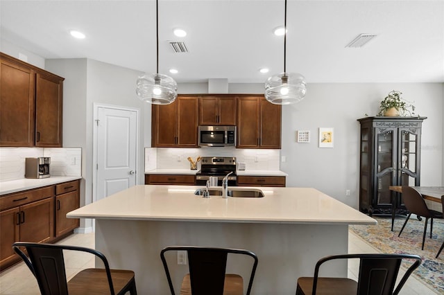 kitchen featuring a breakfast bar, a sink, tasteful backsplash, stainless steel appliances, and light countertops