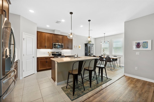 kitchen featuring a breakfast bar area, visible vents, a sink, light countertops, and appliances with stainless steel finishes