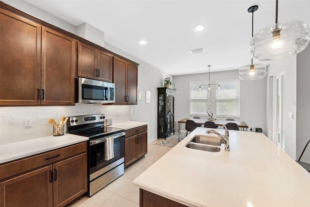 kitchen with visible vents, a sink, tasteful backsplash, stainless steel appliances, and light countertops