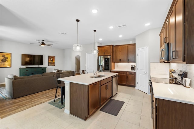 kitchen featuring a breakfast bar area, a sink, stainless steel appliances, light countertops, and backsplash