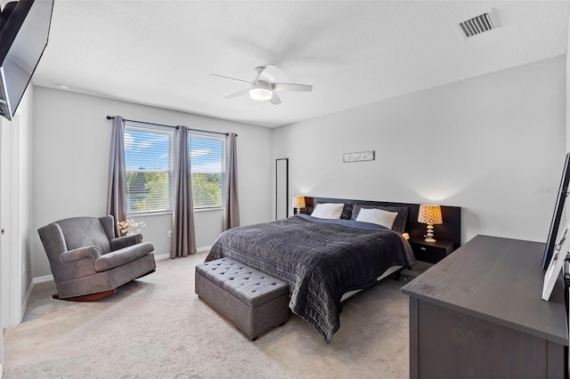 bedroom with visible vents, light colored carpet, baseboards, and ceiling fan